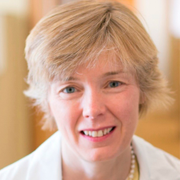 Woman wearing white lab coat with a smile.