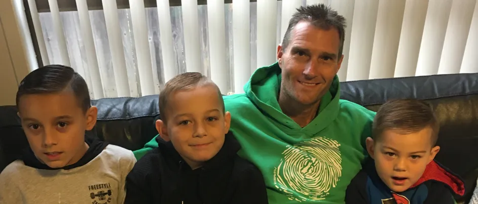 Michael sitting on the couch with his three grandsons
