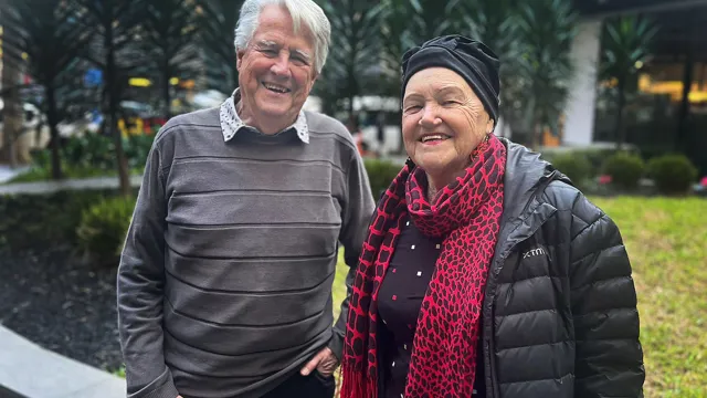 Ross and Marianne Allan, a husband and wife, standing side by side smiling.