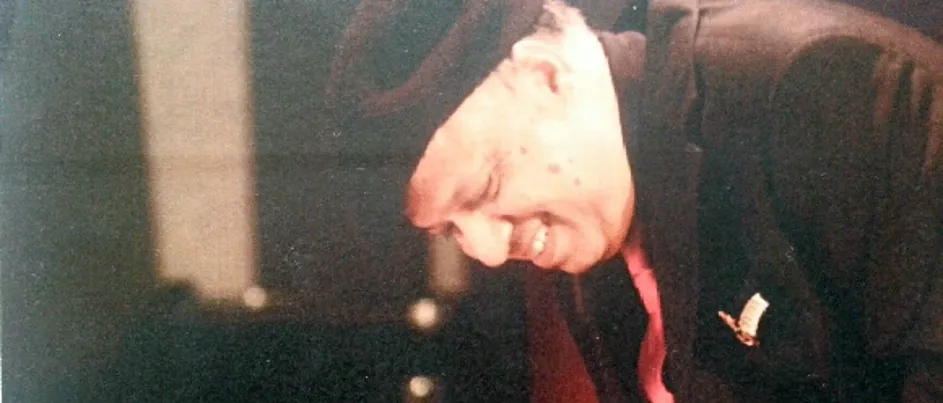 Brad's dad wearing a black suit with a red tie.