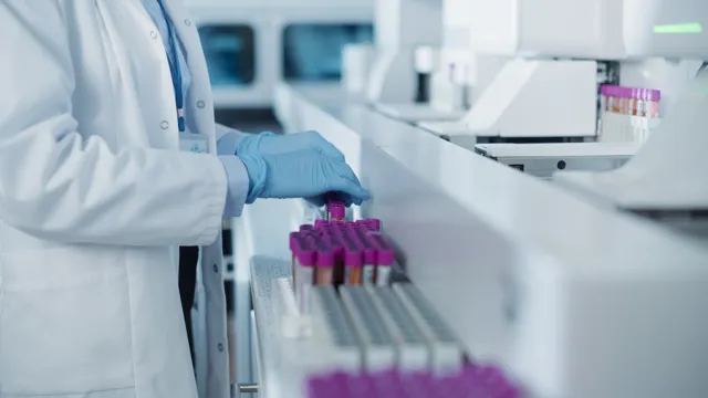 A laboratory technician wearing a lab coat and blue gloves organizing blood sample vials in a high-tech medical laboratory.