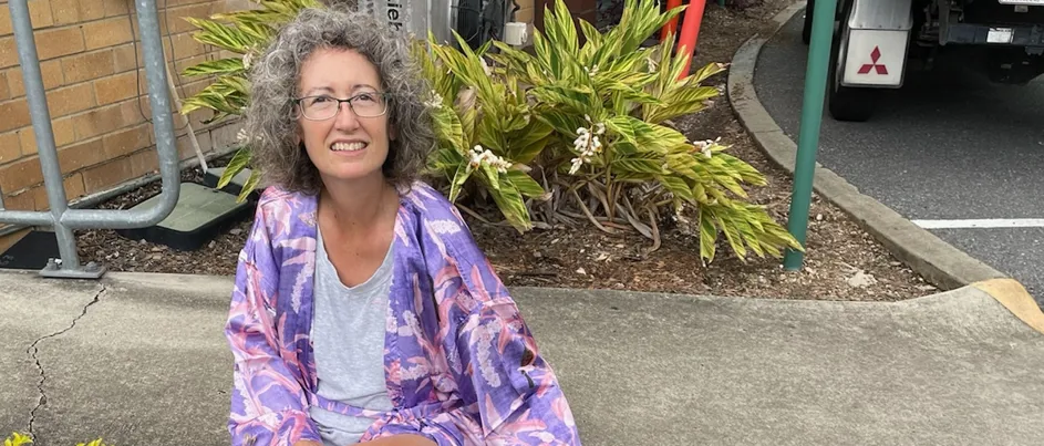 Judi, sitting on the grass next to her dog.