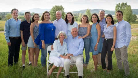 Kelly and Kathy taking a family photo in a field.