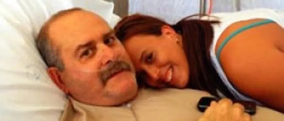 Katrina smiling next to her dad who is laying in a hospital bed.