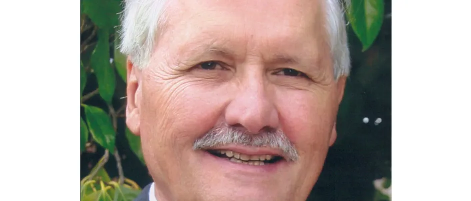 Nicholas, Vassie's father, smiling in front of a garden.
