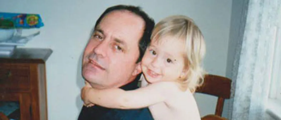 Jess as a child holding onto her father who is wearing a navy blue shirt.