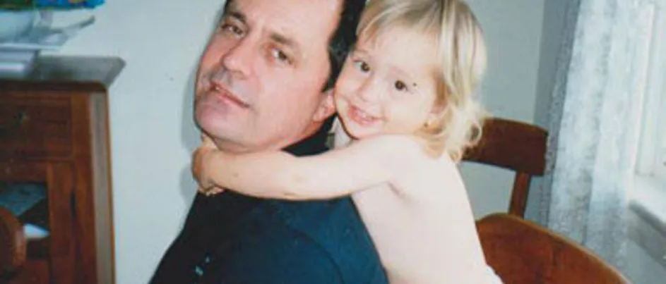 Jess as a child holding onto her father who is wearing a navy blue shirt.