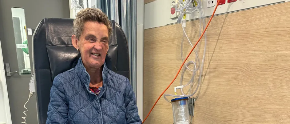 Leanne sitting on a hospital chair with 'Ester' her guide dog by her side.