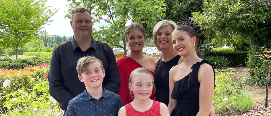 Melissa standing with her family in a garden.