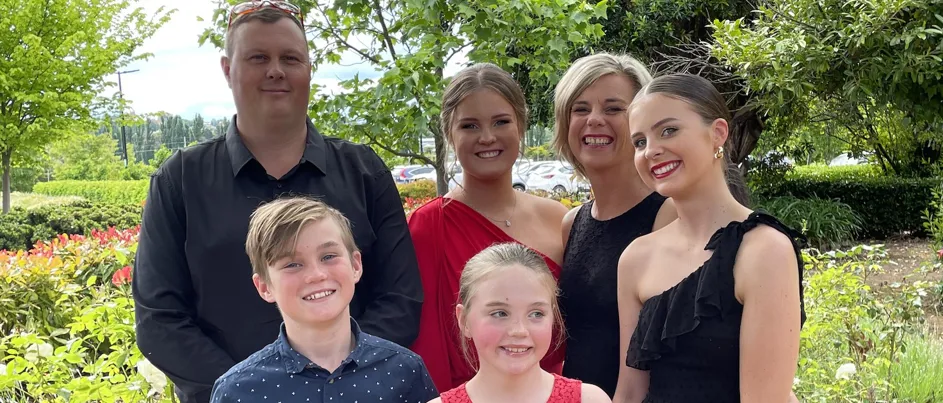 Melissa standing with her family in a garden.