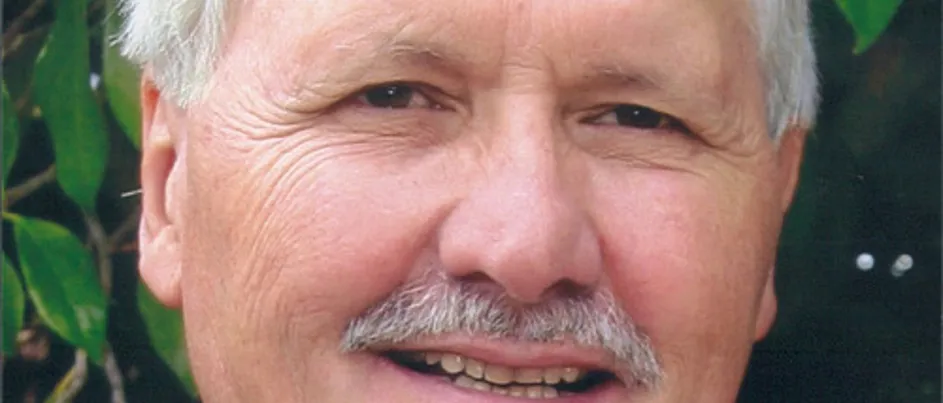 Nicholas, Vassie's father, smiling in front of a garden.