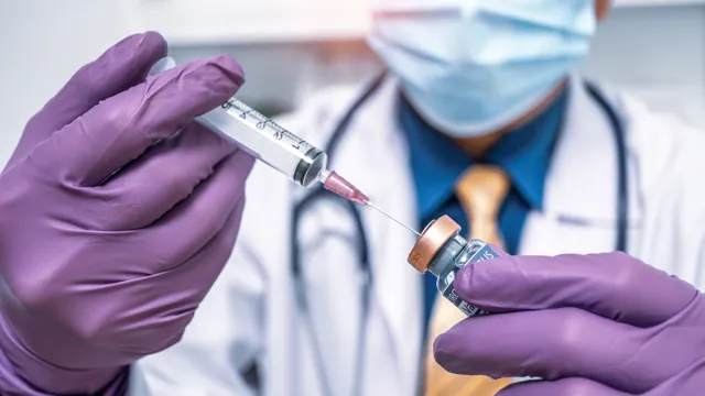 A laboratory researcher wearing a lab coat and blue gloves organizing samples in a high-tech medical laboratory.