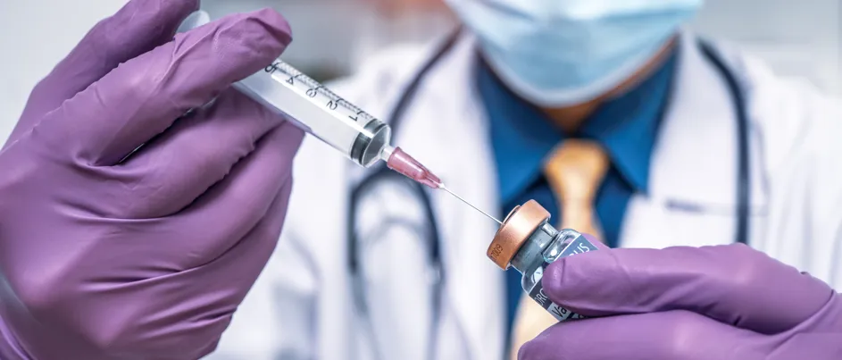 A laboratory researcher wearing a lab coat and blue gloves organising sample vials in a high-tech medical laboratory.