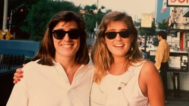 Kathy and Kelly, standing on the street, smiling at the camera.